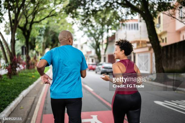 pareja joven corriendo en la calle - carrera de carretera fotografías e imágenes de stock
