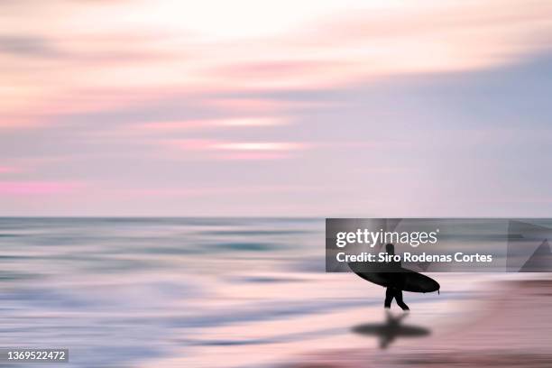 surfer with surfboard entering the sea at sunset in a magical environment - surfers in the sea at sunset bildbanksfoton och bilder