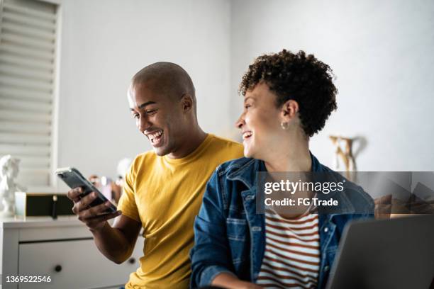 husband showing something on the mobile phone to his wife at home - real wife sharing 個照片及圖片檔