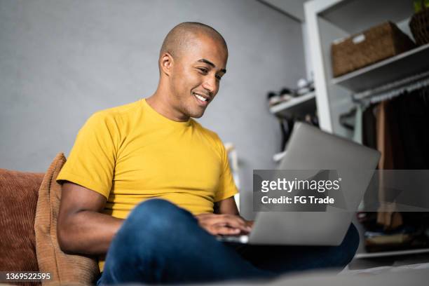 young man using the laptop in the bed at home - bald man stock pictures, royalty-free photos & images