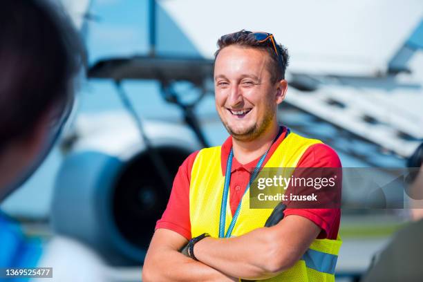 flughafen-bodendienst, junger mann vor flugzeug - airport ground crew uniform stock-fotos und bilder