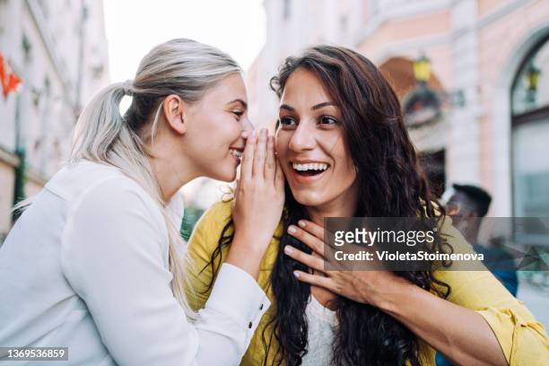 two female young friends sitting in city cafe and gossiping. - telling tales stock pictures, royalty-free photos & images
