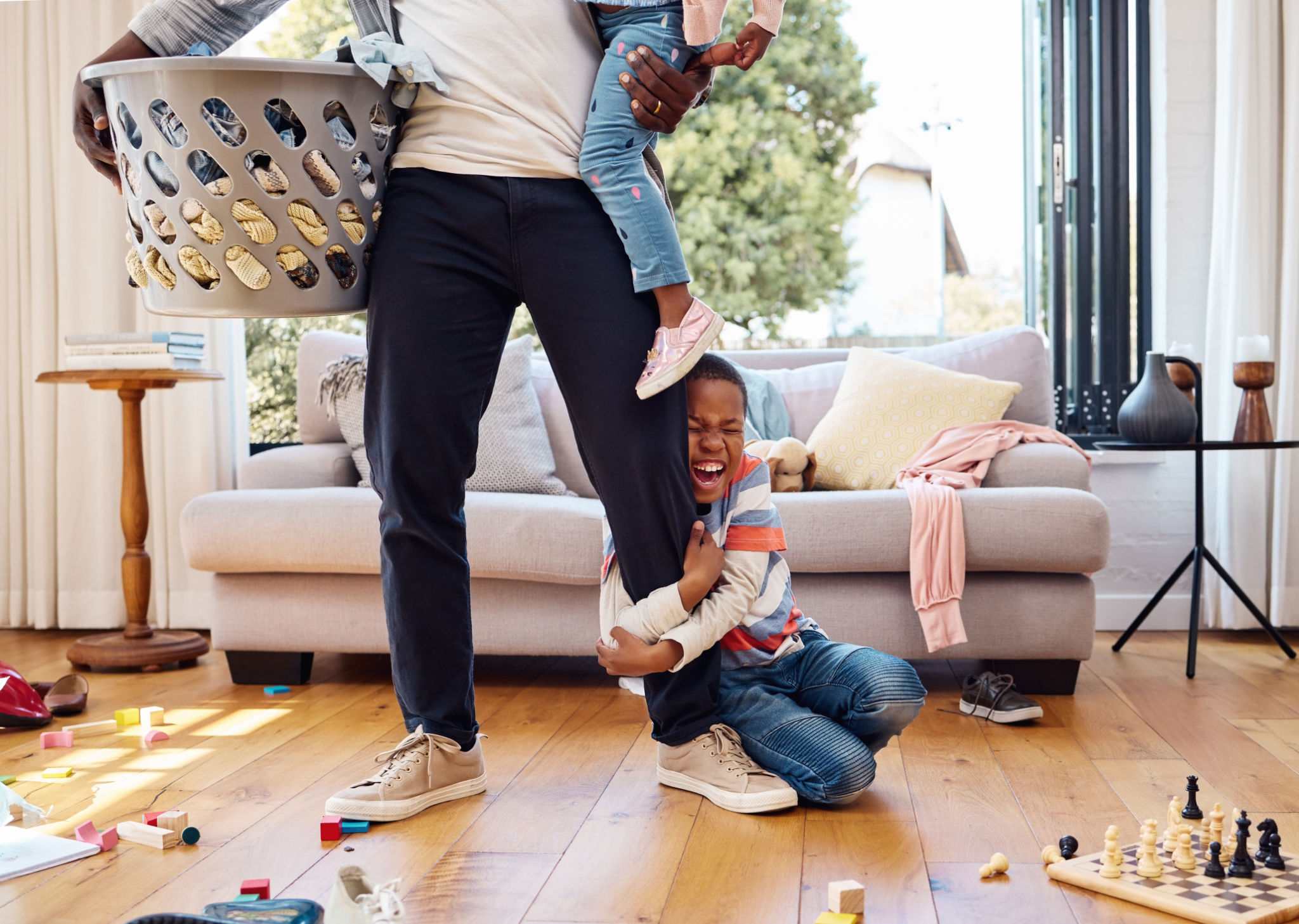 Shot of a little boy throwing a tantrum while holding his parent's leg at home Shot of a little boy throwing a tantrum while holding his parent's leg at home