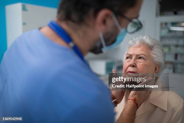 doctor checking senior woman's lymph nodes in doctor´s office. - swollen stock pictures, royalty-free photos & images