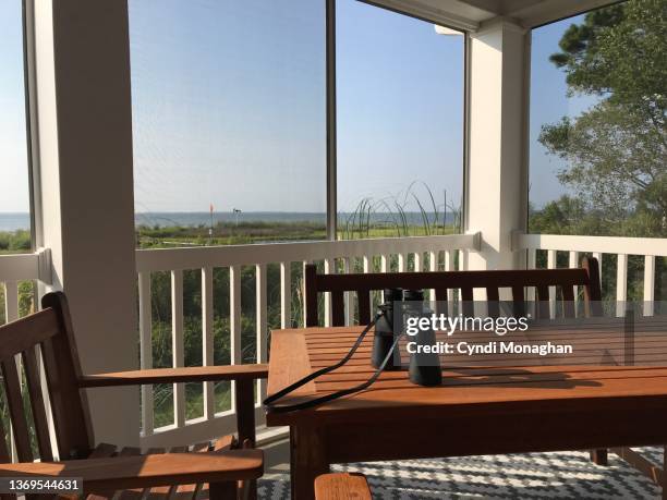 binoculars on a table looking out over a marsh area on the eastern shore of the chesapeake bay. view through a screen window of a porch looking out over the chesapeake bay - beach cottage stock-fotos und bilder