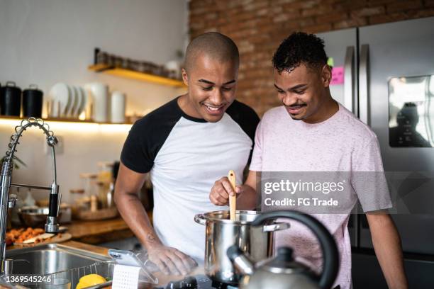 amigos cocinando juntos en casa - hombre gay fotografías e imágenes de stock