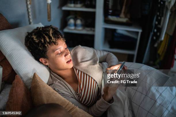 young woman using smartphone on the bed - candid forum stockfoto's en -beelden