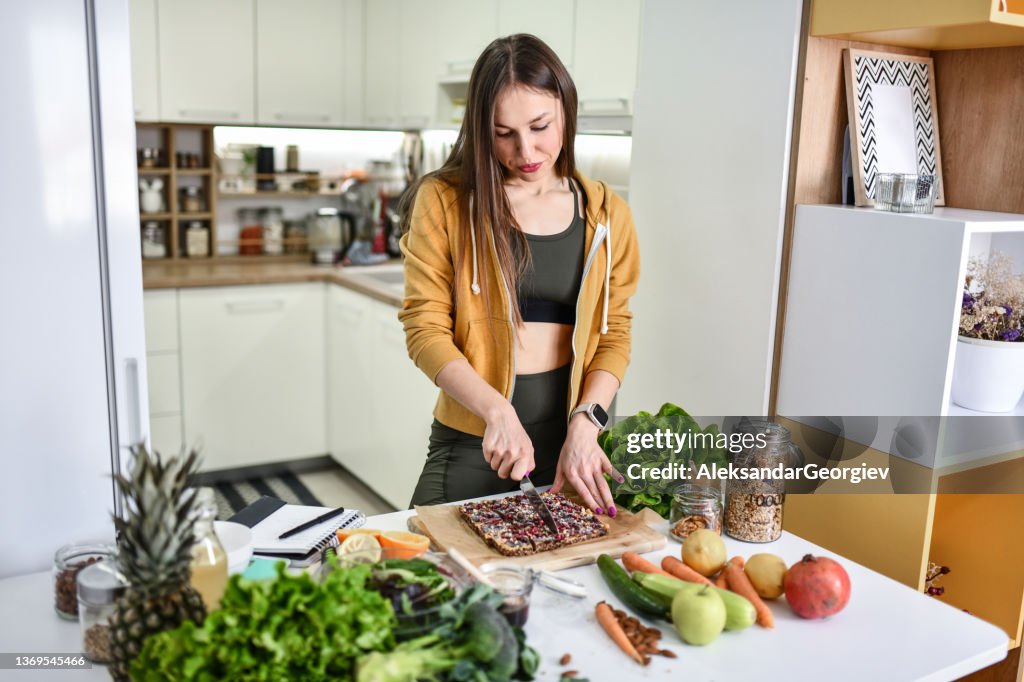 Fit Female Cutting Oat Cake In Pieces For Lunch In Kitchen