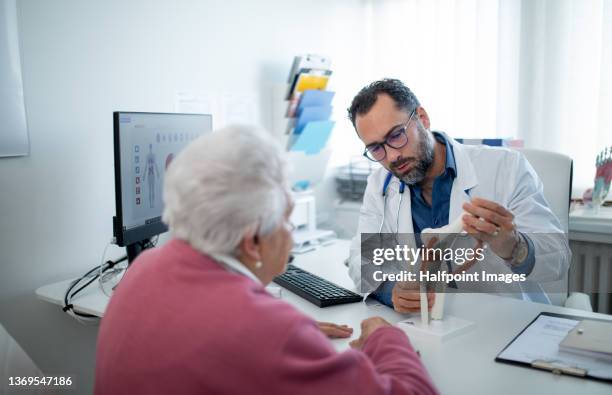 senior woman on consultation with orthopedic doctor in his office. - fake hospital stock-fotos und bilder