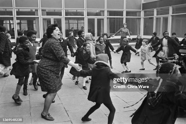 Young students playing ring-a-ring-o'-roses with their teachers in the outside courtyard of West Park Primary School in Wolverhampton, UK, 1968.