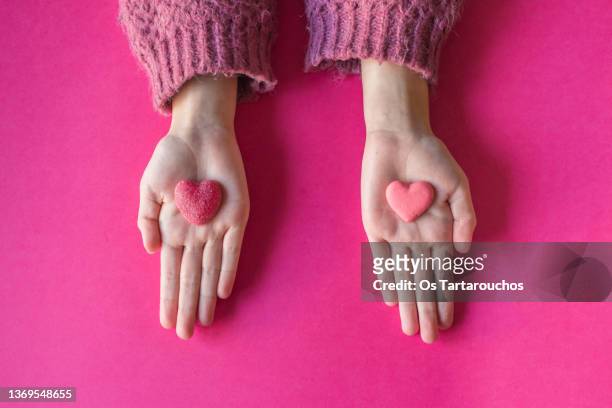 hands separated holding two different candy hearts - holding two things foto e immagini stock