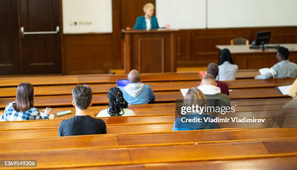 group of students are listening to their professor in the university lecture hall - attending college stock pictures, royalty-free photos & images