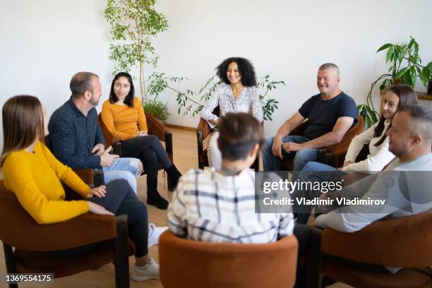 un grupo de terapia que tiene una discusión - member meeting fotografías e imágenes de stock