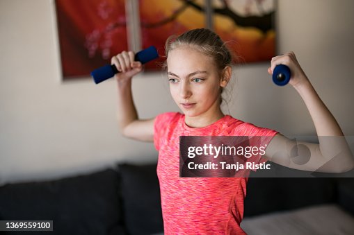 Jolie fille faisant de l’exercice avec des haltères à la maison Jolie fille faisant de l’exercice avec des haltères à la maison