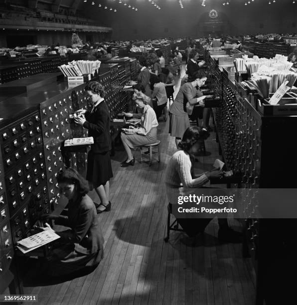 Female employees work with multiple sheets of fingerprints to search for names of suspects from a collection of eight million record cards stored in...