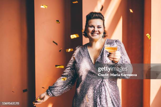 smiling woman holding champagne glass and throwing confetti. - fat woman dancing stock pictures, royalty-free photos & images