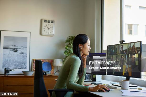 entrepreneur discussing with colleagues on video call - asian man sitting at desk ストックフォトと画像