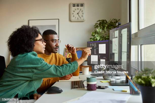 multiracial colleagues discussing over computer - entrepreneurship stock-fotos und bilder