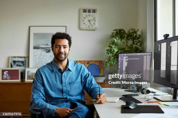 confident businessman sitting at desk in home office - office front desk stock-fotos und bilder