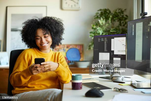 businesswoman using smart phone at home office - donna sorride cellulare foto e immagini stock