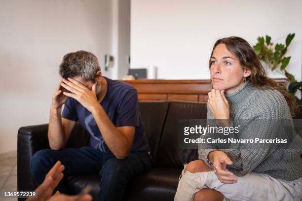 man doing a desperate gesture during couple's therapy with a psychologist - scheidung stock-fotos und bilder