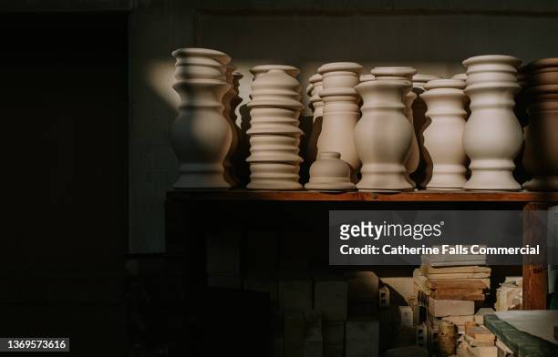 various shaped, unglazed vases / urns sit in a row, illuminated in sunlight - pottery stock-fotos und bilder