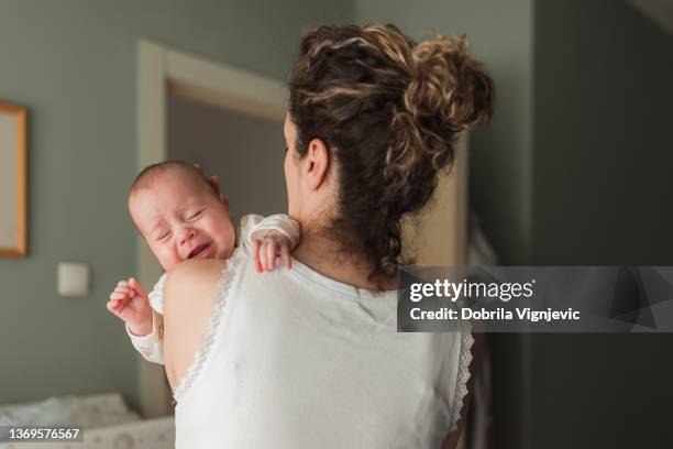 woman taking car of a crying newborn baby - crying baby stock pictures, royalty-free photos & images