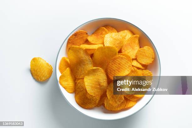 crispy fried potato chips in a bright ceramic bowl or plate, on a white background or table. corn spicy fatty chips with paprika and spices. the concept of unhealthy diet and lifestyle, accumulation of excess weight. copy space. background of food. - excess product stock pictures, royalty-free photos & images