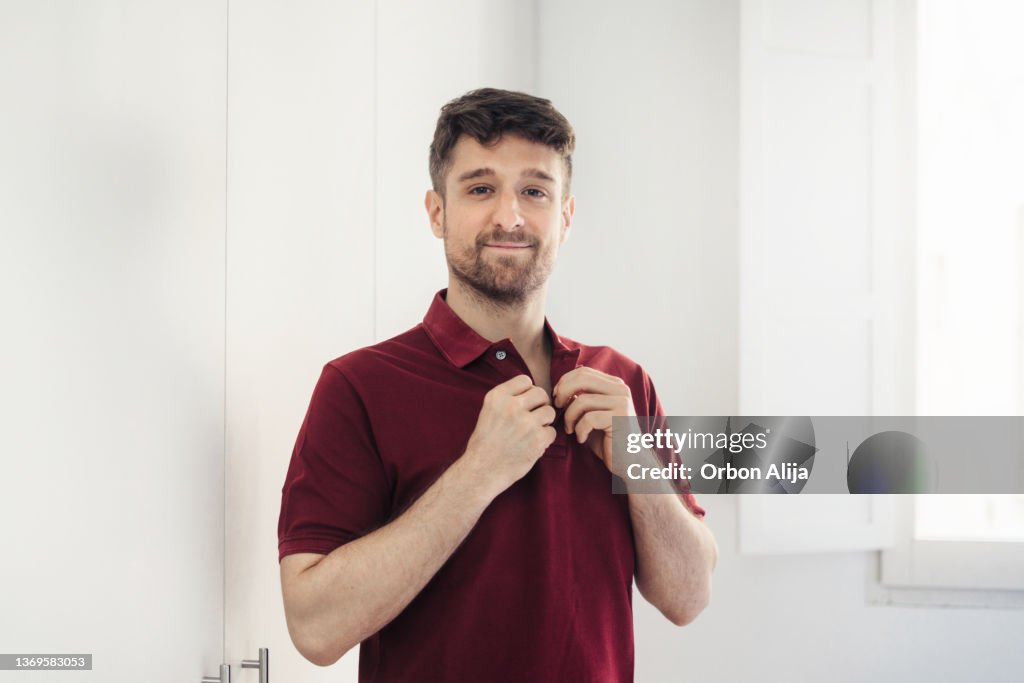 Man buttoning polo shirt
