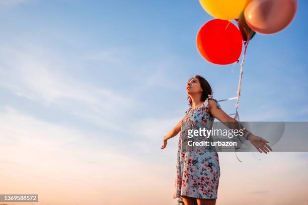 donna che tiene un gruppo di elio palloncini all’aperto - releasing foto e immagini stock