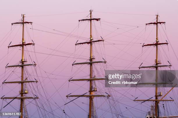 foremast, main mast and mizzen mast of an old wooden tall sailboat with ship rigging against a beautiful purple sky at sunset. yacht background with ropes and shrouds and folded sails - bateau 3 mats photos et images de collection
