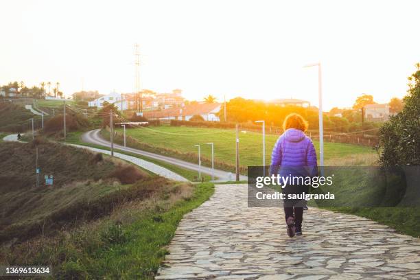 woman seen from behind walking along a path at dawn - gijon stock pictures, royalty-free photos & images