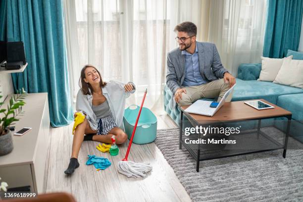 ambitious husband working from home while his wife is cleaning their living room - husband cleaning stock pictures, royalty-free photos & images