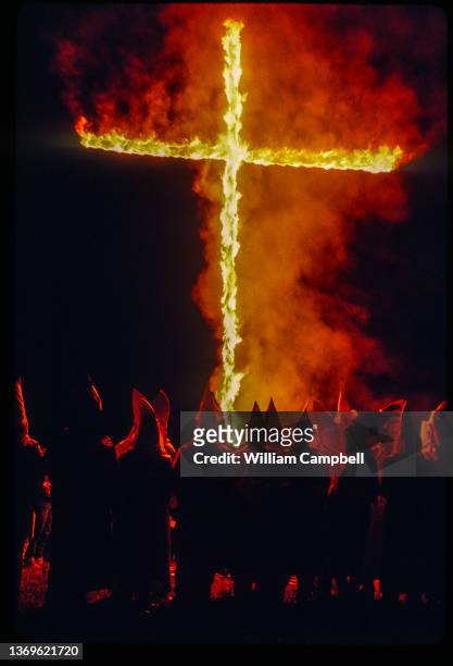 Nighttime view of Ku Klux Klan members as they gather around a large, burning cross during a rally, Tylertown, Mississippi, February 1991.