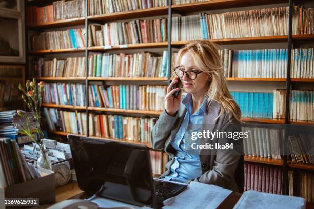 a middle-aged woman in a library - librarian stock pictures, royalty-free photos & images