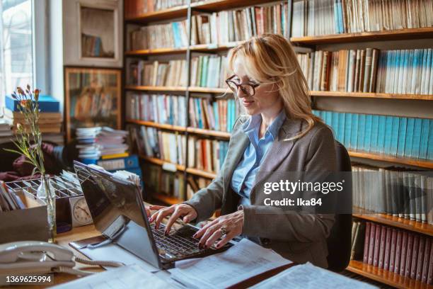 a middle-aged woman in a library - librarian stock pictures, royalty-free photos & images