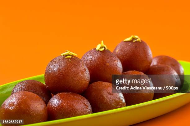 indian dessert gulab jamun in plate on orange background - gulab jamun stock pictures, royalty-free photos & images