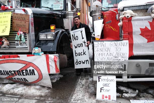 Man holds a sign as truck drivers and their supporters gather to block the streets as part of a convoy of truck protesters against COVID-19 mandates...