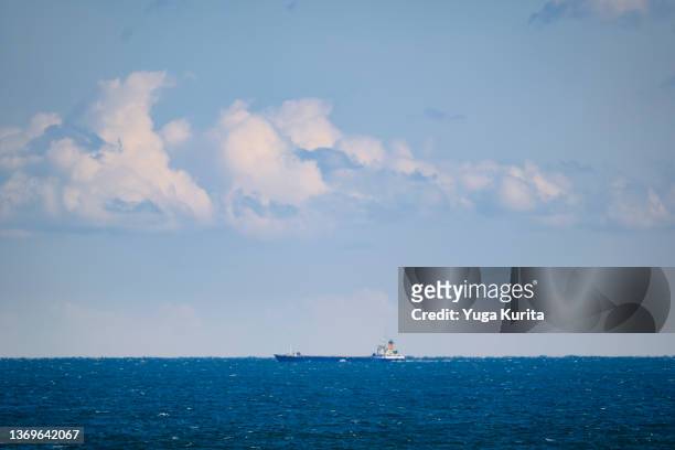white clouds in a blue sky over a horizon of the blue waters of the pacific ocean with a freighter floating at the center - sea ​​of ​​clouds stock pictures, royalty-free photos & images