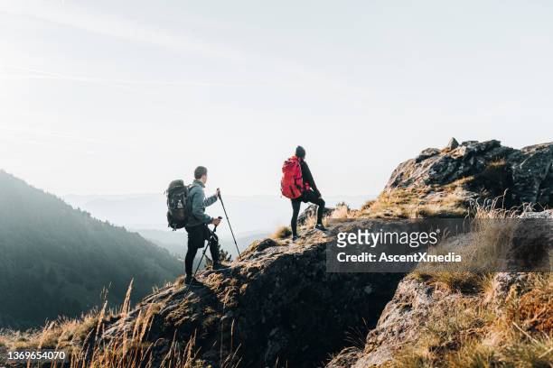 young couple backpack up a mountain summit - hiking pole stock pictures, royalty-free photos & images