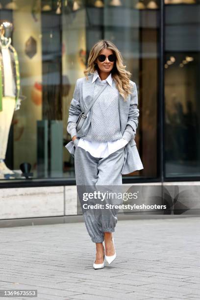 Influencer Gitta Banko wears a grey mesh knit pullover by Brunello Cucinelli, a white blouse by Brunello Cucinelli, a grey jacket by Brunello...