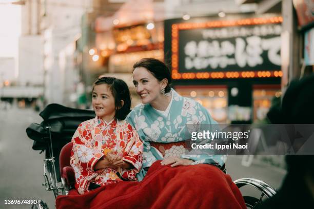 mother and daughter in kimono on rickshaw ride, tokyo, japan - tokyo travel destinations stock-fotos und bilder