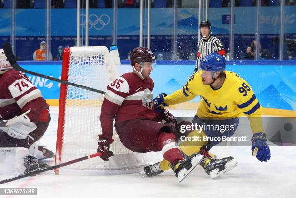 Oskars Batna of Team Latvia and Jacob de la Rose of Team Sweden collide behind the Latvian net in the first period during the Men's Ice Hockey...