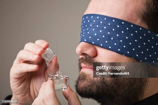 blinfolded man smelling a perfume - blinddoek stockfoto's en -beelden