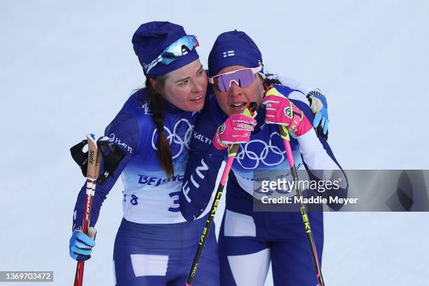 Kerttu Niskanen of Team Finland is embraced by teammate Krista Parmakoski of Team Finland after finishing during the Women's Cross-Country 10km...