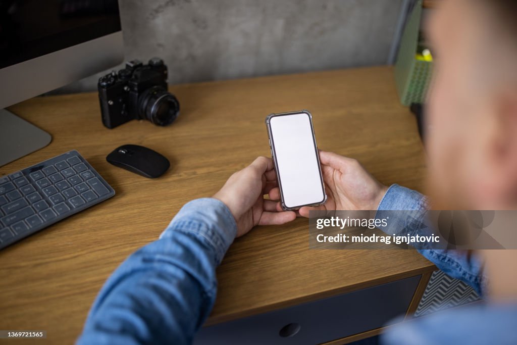 Unrecognizable man holding mobile phone with white device screen