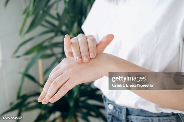 woman with nude pink manicure  squeezing cream on hand's skin to moisturize it. concept of home body care and healthy lifestyle. - hand cream 個照片及圖片檔