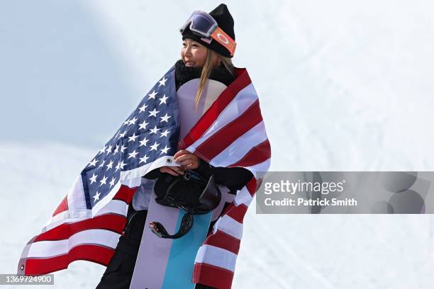 Gold medallist Chloe Kim of Team United States looks on as she is wrapped in a U.S. Flag o the podium for the flower ceremony after winning the...