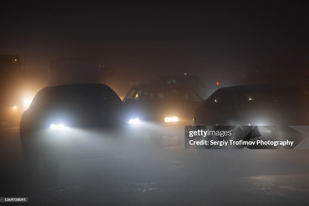 Car driving in the fog on city road at night