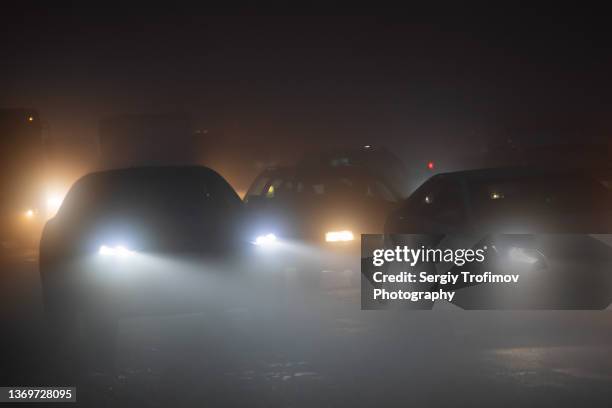 car driving in the fog on city road at night - compact car stockfoto's en -beelden